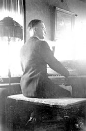 Gerhard Jr. playing Dad's piano, circa mid-1930s, with Theresia's painting of Jesus above piano.